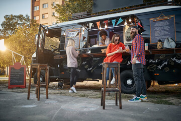 hipster with friends in front of modified truck for mobile fast food service