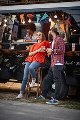 Fototapeta na wymiar urban caucasian couple flirting in front of modified truck for mobile fast food service