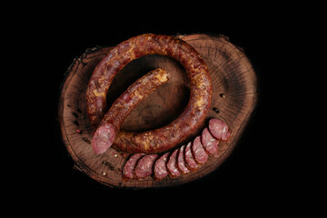 Whole fresh smoked sausage on a dark background, circle and slices