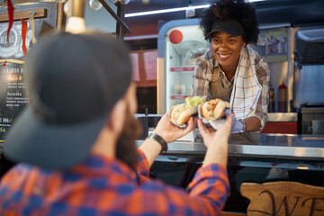 close up of sandwiches with green salad and mustard.  male receiving from a smiling employee in...