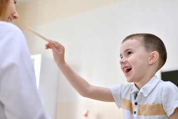 The child cheerfully smiling pulls his hand with a spatula to the doctor in white uniform.