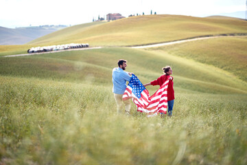 A couple in love strolling a field with the American flag. Election, campaign, freedom concept
