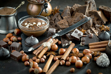 Dark chocolate in a composition with cocoa beans and nuts, on an old background.