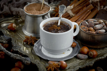 Hot chocolate on an old background in a composition with cocoa beans and nuts.