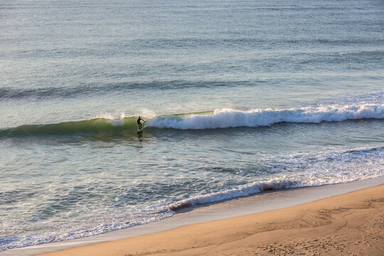 Surfer silhouetted riding wave at Whitecrest Beach in Wellfleet, MA