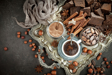 Hot chocolate on an old background in a composition with cocoa beans and nuts.