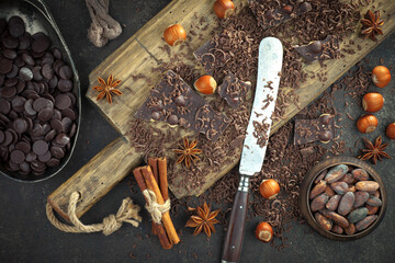 Pieces of dark chocolate and cocoa beans in composition on old background