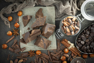 Pieces of dark chocolate and cocoa beans in composition on old background