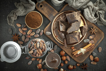 Pieces of dark chocolate and cocoa beans in composition on old background