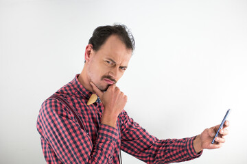 Portrait of caucasian man in middle age. Wearing shirt and wooden bowtie. Studio photo with white background. Holding cell phone in the hand and writing sms message. Looking to the camera.