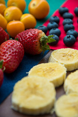 Fresh fruit on a colorful surface like sliced banana strawberries and blueberries 