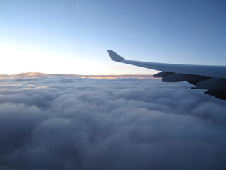 Fototapeta na wymiar Airplane wing during flight above the clouds. Clear sky in the distance