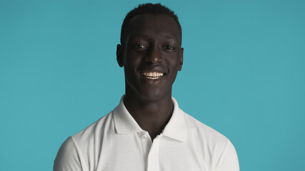 Obraz premium African American man in white T-shirt looking happy isolated on blue background