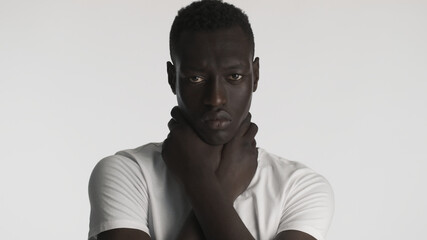 Obraz premium Young African American man holding hands on neck aggressively looking in camera over white background. Choke expression. Black lives matter