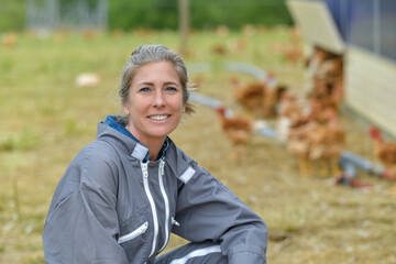 Portrait of a smiling female farmer standing in the middle of her chicken farm