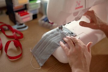 Woman hands using the sewing machine to sew the face mask