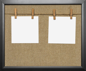 Close-up of two blank notes hanged by pegs on a washing line against natural jute background....