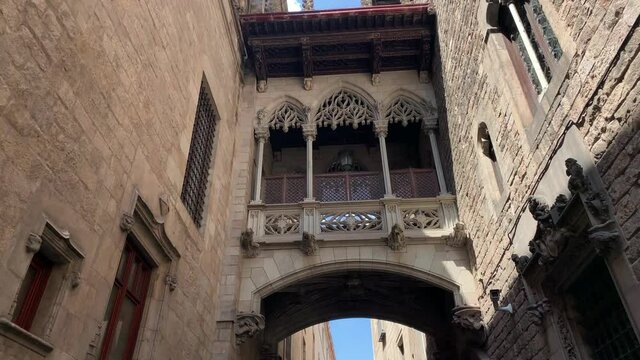 Footage of Bishop's Bridge (Pont Gotic) in "Ciutat Vella" district (Gothic Quarter) in Barcelona. It is a sunny summer day. Camera moves forward.