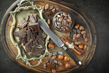 Pieces of dark chocolate and cocoa beans in composition on old background