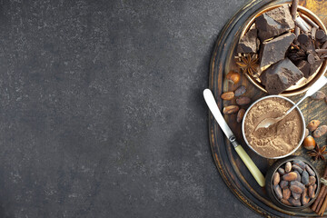 Pieces of dark chocolate and cocoa beans in composition on old background