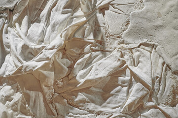 Fabric texture, soft, low-contrast, slightly toned conceptual image of white fabric prepared in plaster solution, low warm toning, specially crumpled, selective sharpness