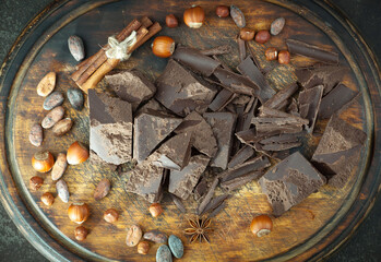 Pieces of dark chocolate and cocoa beans in composition on old background