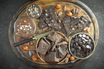 Pieces of dark chocolate and cocoa beans in composition on old background