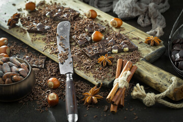 Pieces of dark chocolate and cocoa beans in composition on old background