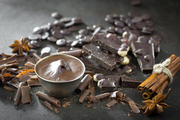 Dark chocolate in a composition with cocoa beans and nuts, on an old background.