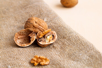 close-up peeled walnuts in shells on a wooden table and in a glass jar. brown nuts on a light background. dried walnut on the sackcloth. copy space.
