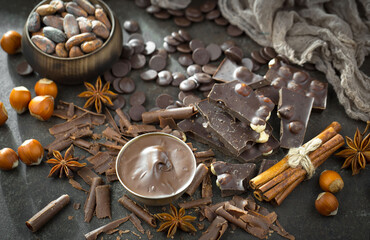 Pieces of dark chocolate and cocoa beans in composition on old background