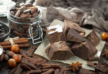 Pieces of dark chocolate and cocoa beans in composition on old background