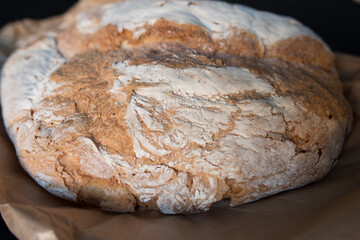 Bread baked in a wood oven. Close up of the piece of bread over the classic caste envelope on a black background.