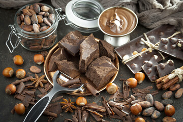 Dark chocolate in a composition with cocoa beans and nuts, on an old background.