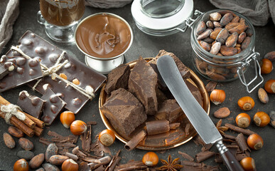Pieces of dark chocolate and cocoa beans in composition on old background