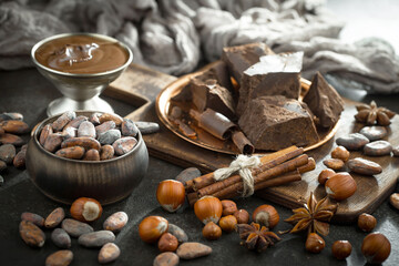 Pieces of dark chocolate and cocoa beans in composition on old background
