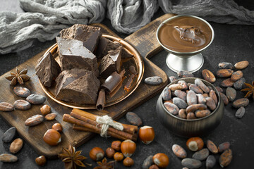 Dark chocolate in a composition with cocoa beans and nuts, on an old background.