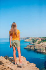 Happy kid outdoor on edge of cliff seashore