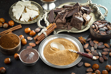 Pieces of dark chocolate and cocoa beans in composition on old background