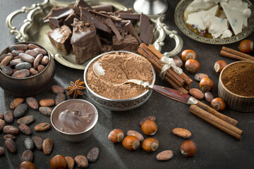 Pieces of dark chocolate and cocoa beans in composition on old background