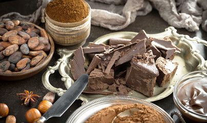 Pieces of dark chocolate and cocoa beans in composition on old background