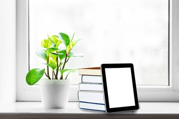 Stack of books with modern digital tablet on table