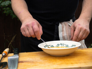 a man in a black apron whips up the yolk of eggs in a plate with a fork.