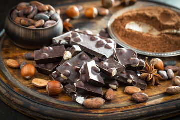 Pieces of dark chocolate and cocoa beans in composition on old background