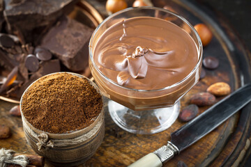 Dark chocolate in a composition with cocoa beans and nuts, on an old background.