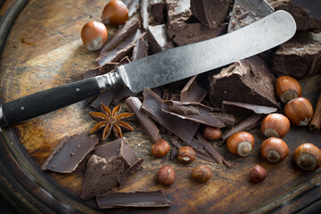Pieces of dark chocolate and cocoa beans in composition on old background