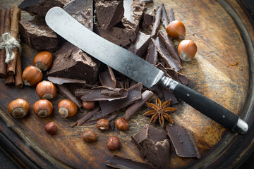 Pieces of dark chocolate and cocoa beans in composition on old background