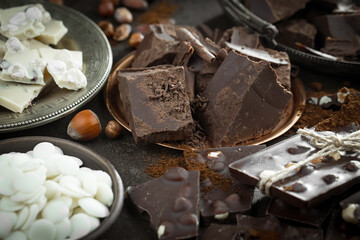 Pieces of dark chocolate and cocoa beans in composition on old background