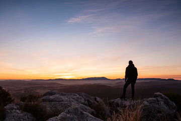 Silhouette of a person at the top of the mountains looking at sunrise