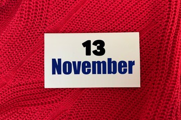 November 13 on a sticker on a red knitted background.Autumn .Calendar for November.